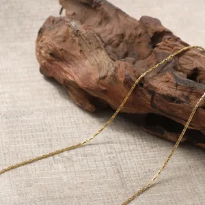 Vista macro di una catena in acciaio inossidabile placcato oro 18K su supporto in legno