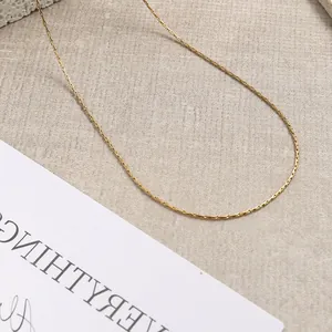 Dettaglio di collana a catena in acciaio inossidabile placcata oro 18K su base beige