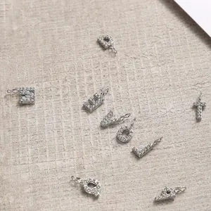 Macro detail of silver letter pendants D E V O L T with micro-pave cubic zirconia crystals