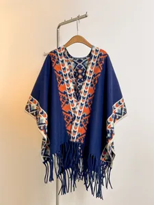 Détail d'un poncho en maille bleu marine avec motif jacquard ethnique et franges
