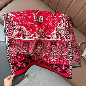 Gros plan d'un châle à motif paisley rouge avec fleurs complexes et finitions franges