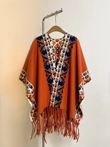 Détail d'un poncho en tricot bohème avec motifs jacquard géométriques et longues franges
