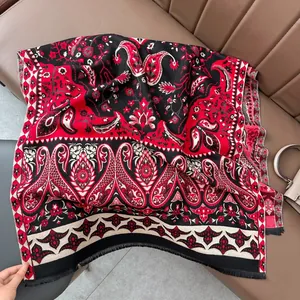 Détail d'un châle cachemire rouge et noir avec motifs paisley et bordures frangées