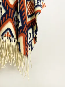 Close-up of bohemian geometric knit shawl with thick texture and white fringe tassels