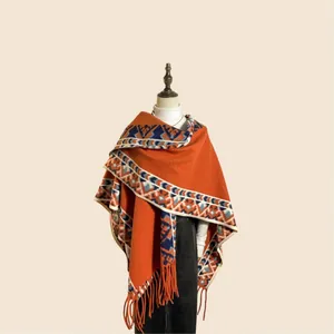 Détail du poncho orange vintage avec motifs jacquard géométriques et bordures frangées
