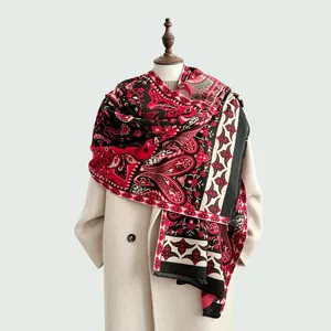 Détail du châle paisley rouge et noir montrant les franges sur un manteau blanc