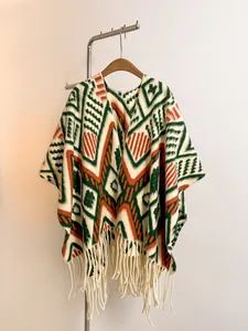 Detail of a thick ethnic knit poncho featuring geometric patterns and hanging tassels