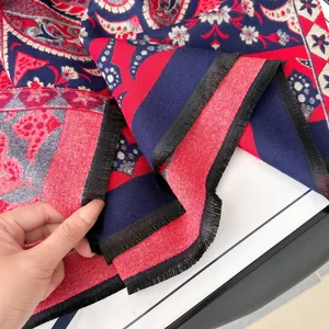Détail montrant les motifs paisley et les franges noires sur le châle rouge et bleu