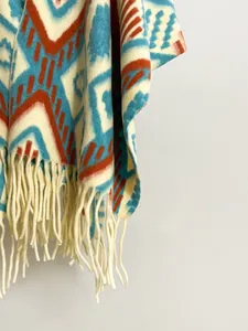 Close-up of thick geometric patterned shawl with cream tassels and ethnic knit texture