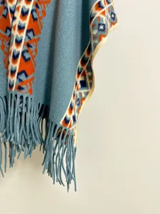 Détail d'un poncho d'automne bleu clair aux motifs ethniques et finitions à franges