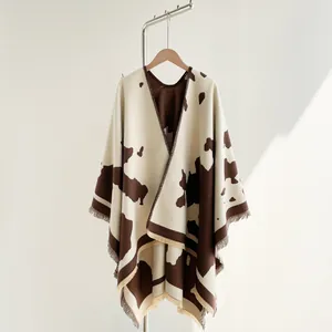 Close-up of cow print poncho shawl featuring thick knit fabric and tassel trim detailing