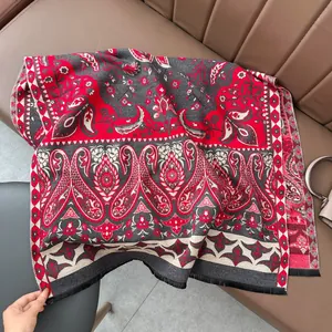 Détail d'une écharpe cachemire à motif paisley rouge et gris avec des franges noires