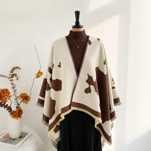 Detail view of the cow print shawl featuring irregular patterns and soft fringe edges