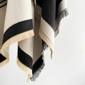 Detail of cream and black striped knit shawl featuring elegant matching tassels and texture
