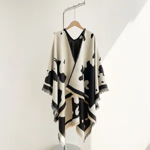 Detail of knitted travel shawl featuring cow print pattern and fringe tassel edges