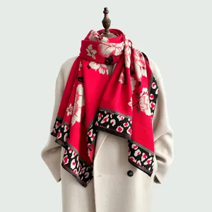 Vintage red floral scarf with leopard print edge and tassels on a beige coat display