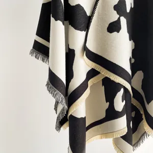 Detailed view of thick cow print knit shawl featuring decorative fringe edges and soft texture