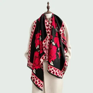 Detail of red floral and leopard print knit scarf with tassel fringe on a white coat