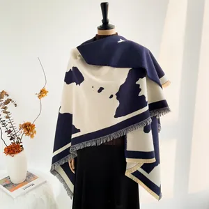 Detailed view of the thick navy and beige block pattern knit shawl with long fringe edge