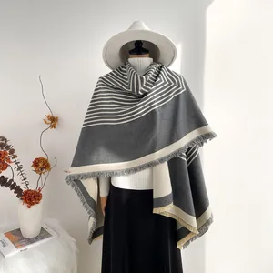 Detail of grey and beige geometric cashmere shawl with fringe trim on model