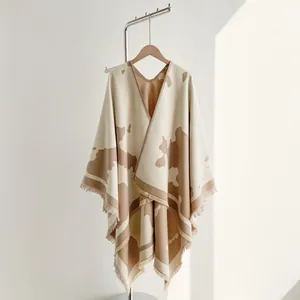 Detail of a thick milk-patterned shawl with tassels in beige and light brown tones