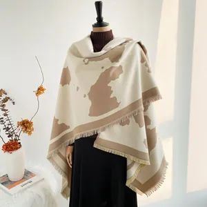 Close-up of thick knit shawl featuring beige and camel color blocks and fringe detail