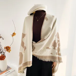 Close-up of soft knitted travel shawl featuring brown milk pattern and fringe details