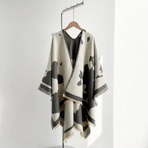 Detail of soft milk pattern knitted shawl with short fringe edges on a wooden hanger