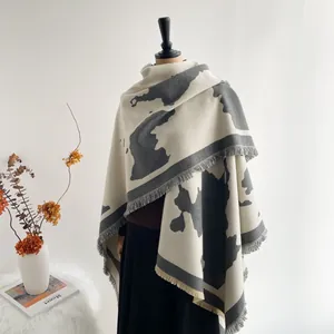 Detail of artistic gray and white milk pattern shawl with soft tassel edges