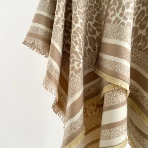 Detail showing the leopard print pattern and delicate fringe on the knit shawl wrap