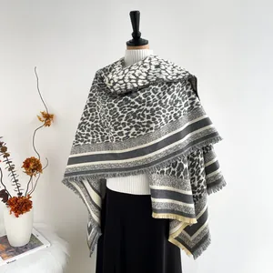 Detail of leopard print faux cashmere shawl featuring striped hem and fringe accents