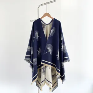 Detailed view of navy and cream knit shawl featuring gingko leaf patterns and tassels