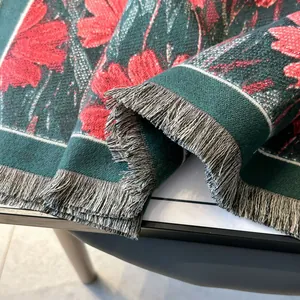 Détail d'une écharpe en jacquard avec motifs floraux, tissu vert et franges