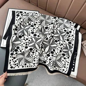 Close-up of black and white floral jacquard shawl with soft fringes on a leather couch