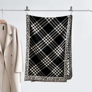 Detail of plaid scarf with leopard print borders and fringes on a beige coat