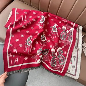 Dettaglio dello scialle jacquard paisley rosso e beige con frange decorative sui bordi