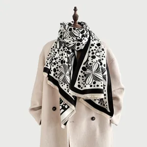 Detail of black and white floral jacquard warm scarf with short tassel hem on a beige coat