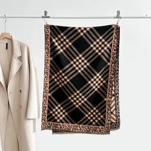Detail of checkered and leopard print scarf with tassels hanging on a metal rack