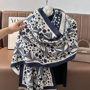Detailed close-up of navy blue and beige jacquard knit scarf with fringe and leaf patterns