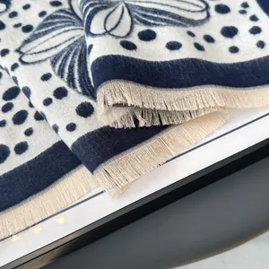 Close-up of floral jacquard pattern and fine short fringe detail on navy blue scarf