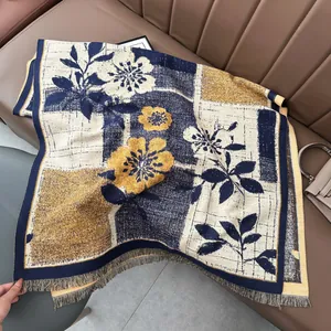 Detail of floral tapestry pashmina with tassels on a brown leather sofa