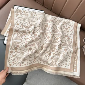 Detail of beige jacquard knit shawl with floral patterns and soft tassel edges