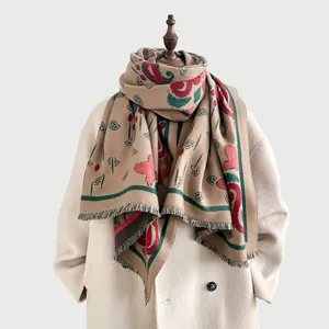 Dettaglio dello scialle bohémien con motivo paisley e frange su un cappotto beige classico