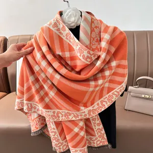 Detail of orange and beige plaid knit shawl with leopard floral patterns and soft fringes