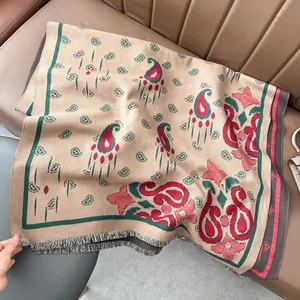 Dettaglio di scialle jacquard bohémien con motivo paisley e frange su divano pelle