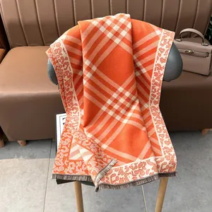 Detailed view of plaid and leopard print scarf with fringe hanging on a leather chair