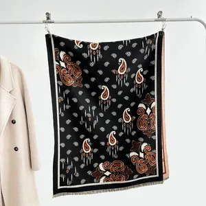 Dettaglio dello scialle jacquard paisley nero e marrone con rifiniture a frange