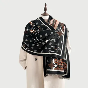 Dettaglio dello scialle jacquard bohémien con motivo paisley e frange su cappotto beige