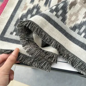 Détail du tissage épais et des franges élégantes de cette écharpe d'hiver beige et grise