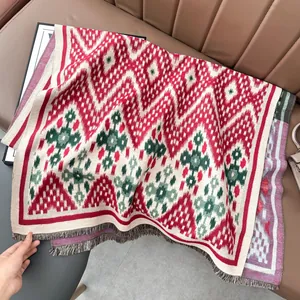 Gros plan d'une écharpe en maille géométrique avec franges sur canapé en cuir